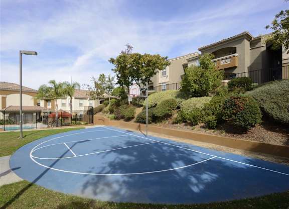 A basketball court is surrounded by apartment buildings.