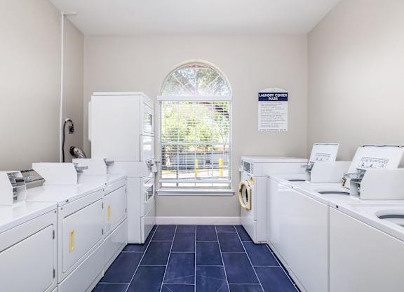 a laundry room with white washers and dryers and a window at Clear Creek Meadows Apartments, Texas, 76522