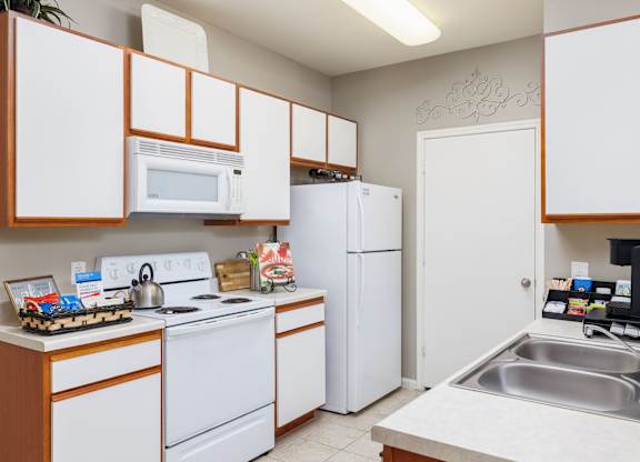 A kitchen with white appliances and wooden cabinets at Clear Creek Meadows Apartments, Copperas Cove, 76522