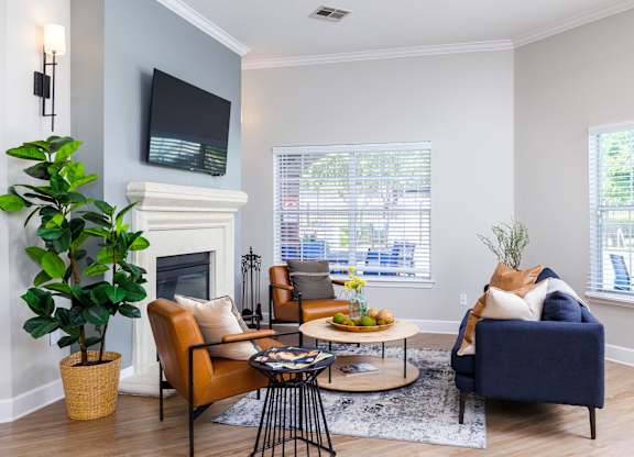 a living room with gray walls and a fireplace with a tv above it at Clear Creek Meadows Apartments, Copperas Cove, Texas