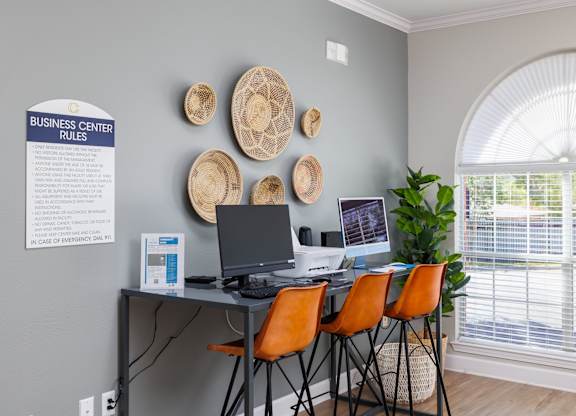 a desk with four orange chairs in front of a large window at Clear Creek Meadows Apartments, Texas