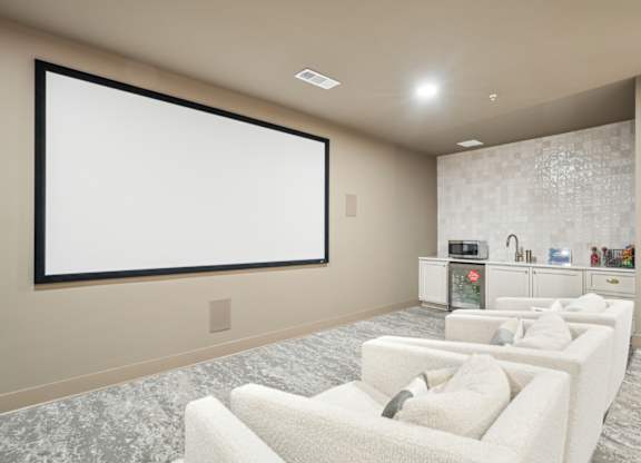 A modern living room with a large screen and comfortable seating.