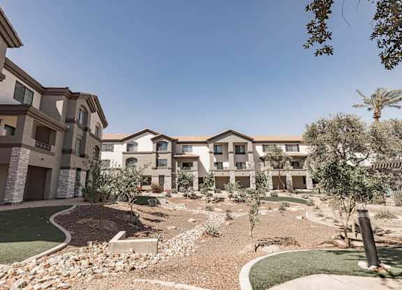 A modern residential complex with a well-maintained garden in front.