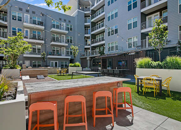 A patio with a table and chairs in front of apartment buildings.