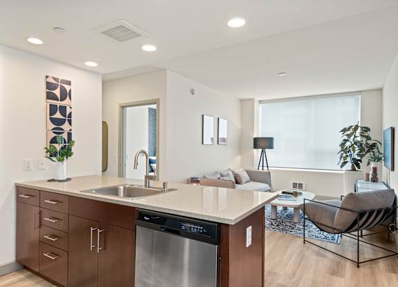 a kitchen with a large center island next to a living room with a couch and a window
