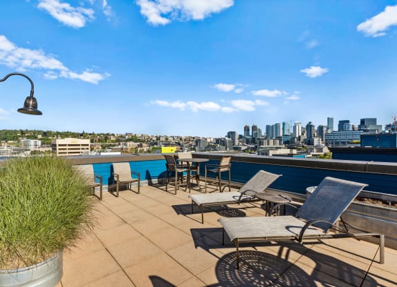 a roof deck with lounge chairs and a table with a view of the city  at Dexter Lake Union, Seattle, Washington