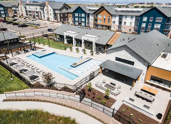 A large outdoor swimming pool surrounded by a black fence and a small building.