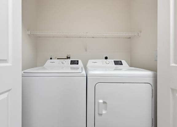 Two white front loading washing machines in a small laundry room.