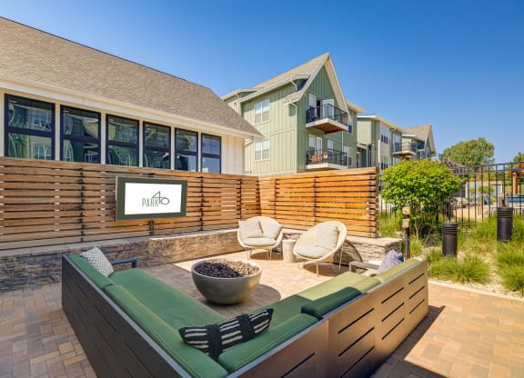 a patio with a couch and chairs in front of a house