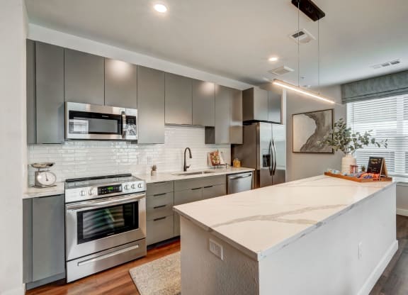 the kitchen has stainless steel appliances and a large white island