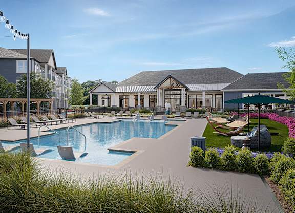 A large outdoor swimming pool surrounded by lounge chairs and umbrellas at Easton at Mountain Island apartments in Charlotte, NC.