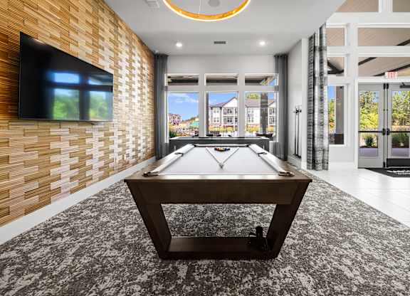 A pool table in a room with a television on the wall.