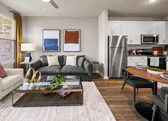 A modern living room with a grey sofa, a coffee table, and a kitchen in the background.