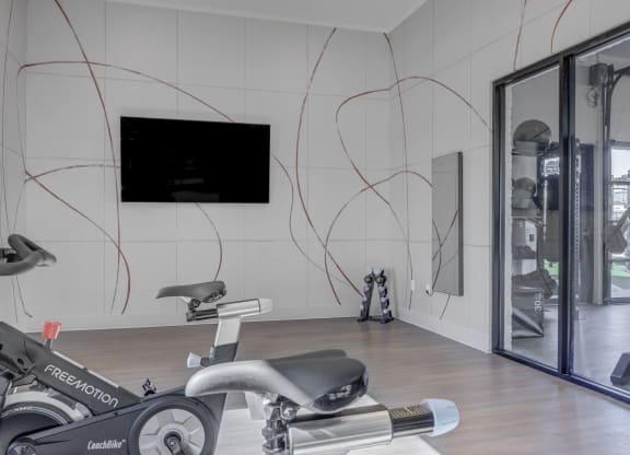 a gym with exercise equipment and a flat screen tv on the wall  at Embold, Lehi, 84043