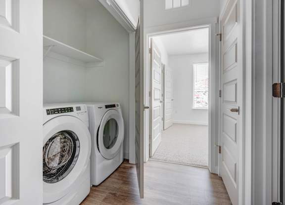 a white washer and dryer in a white laundry room with a door open