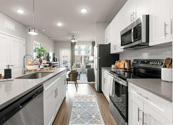 A modern kitchen with white cabinets and black appliances.