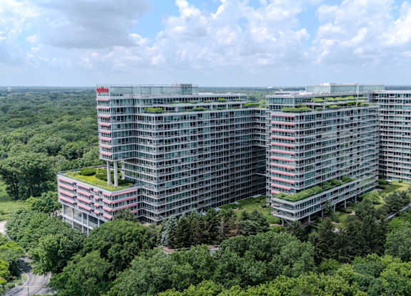A large building with a green roof is surrounded by trees.