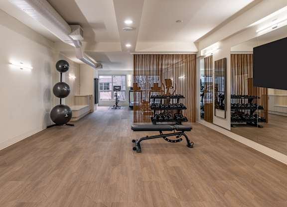a room with a chair and a tv in the corner and a wood flooring