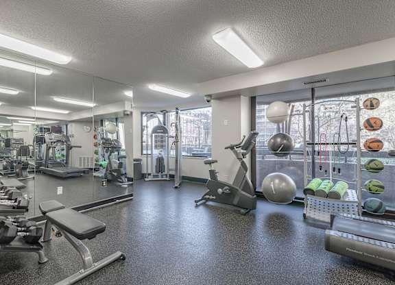 a gym with exercise equipment and weights on the floor and a mirrored wall