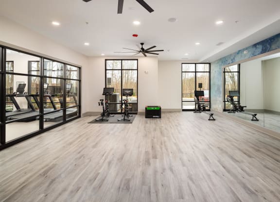 a fitness room with mirrors and chairs and a reformer