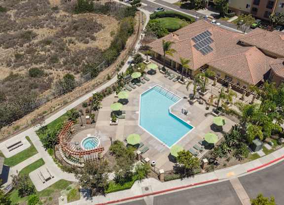 A large swimming pool surrounded by a grassy area and a building with a red roof.