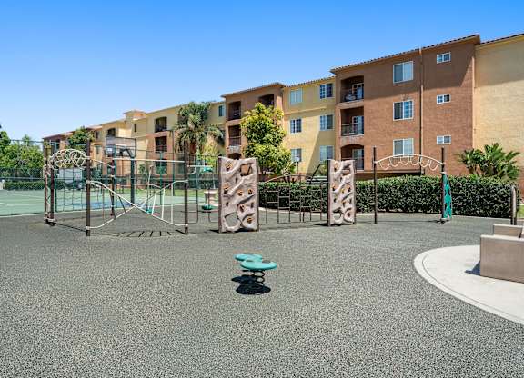 A playground with a blue bench in the middle of a grey ground.