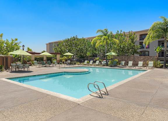 A large swimming pool surrounded by chairs and umbrellas.