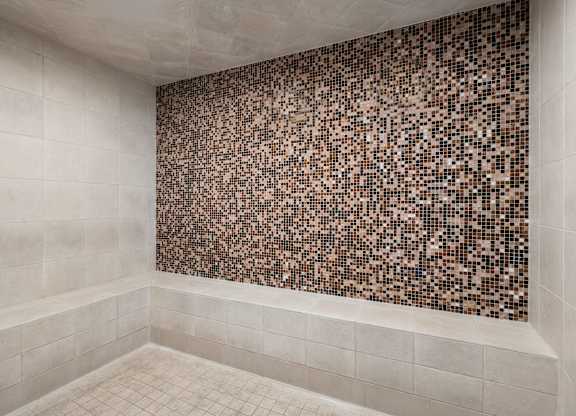 Spa with a brown tile wall and white tiled floor.