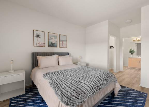 A bedroom with a bed, nightstand, and pictures on the wall.