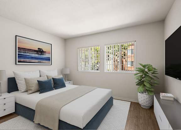 A bedroom with a large bed, a nightstand, a lamp, a potted plant, and a framed picture on the wall.
