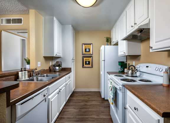 A kitchen with white cabinets and a fridge.