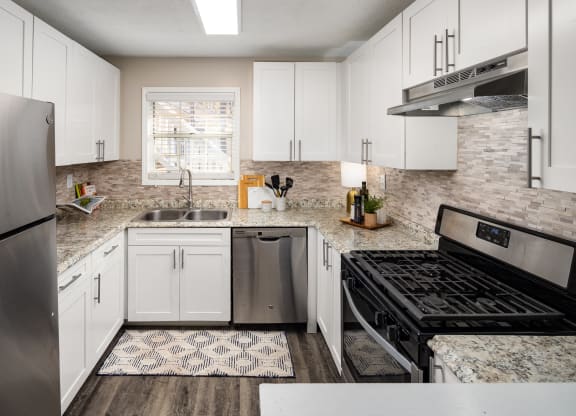 an updated kitchen with white cabinets and stainless steel appliances