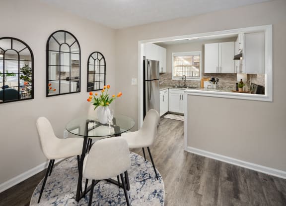a dining room with a glass table and chairs and a kitchen