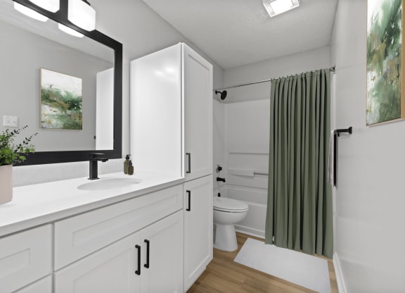 a bathroom with white cabinets and a green shower curtain