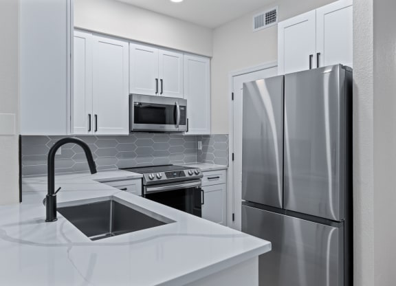 a kitchen with white cabinets and stainless steel appliances