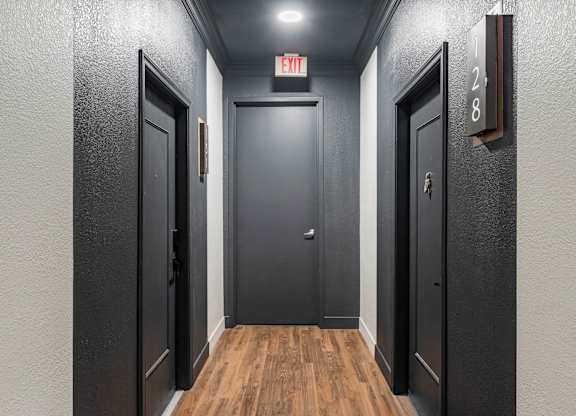 A hallway with doors on both sides and a sign above the middle door.