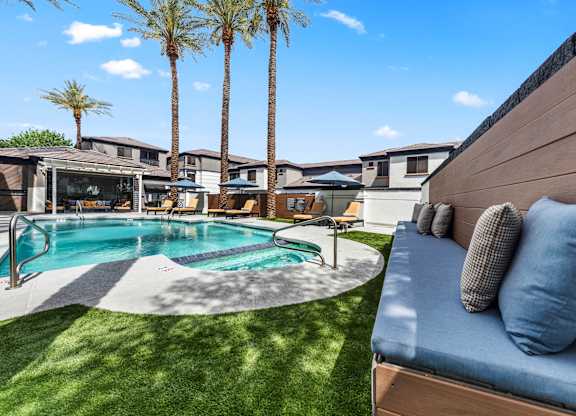 A pool surrounded by palm trees and a wooden bench.