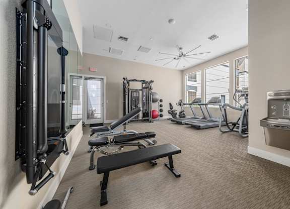 A gym with a variety of equipment including a treadmill, weights, and a bench.