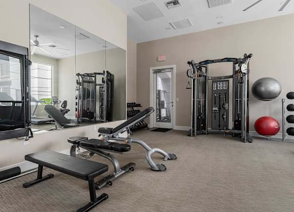 A gym with a variety of equipment including a leg press machine, a bench, and a medicine ball.