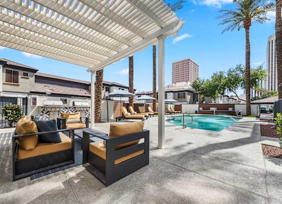 A patio with a pool and a white pergola.