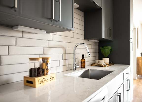 A kitchen with a marble countertop and a coffee bar.