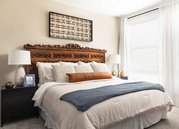 A bed with a white comforter and a blue throw is in the center of the image.