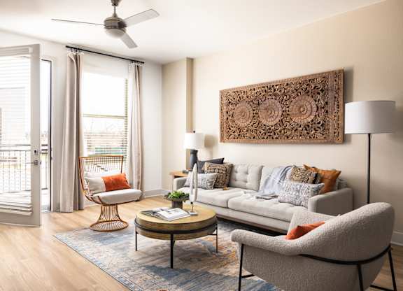 A living room with a grey couch, a coffee table, a chair, and a ceiling fan.