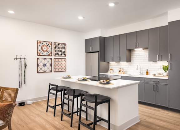 A kitchen with a white counter and black bar stools.