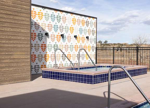 A pool with a tile wall and a black fence.