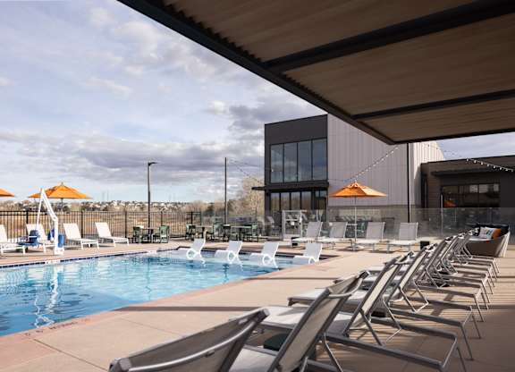 A pool with chairs and umbrellas in front of a building.