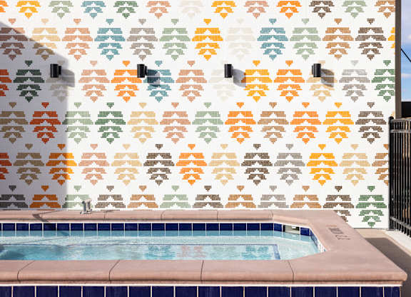 A pool with a wall that has a pattern of leaves on it.