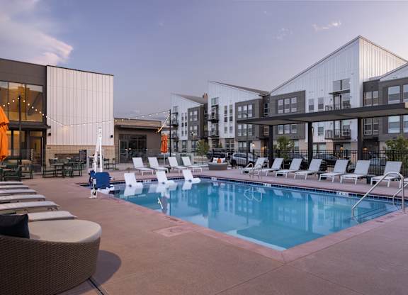 A pool surrounded by lounge chairs and umbrellas.