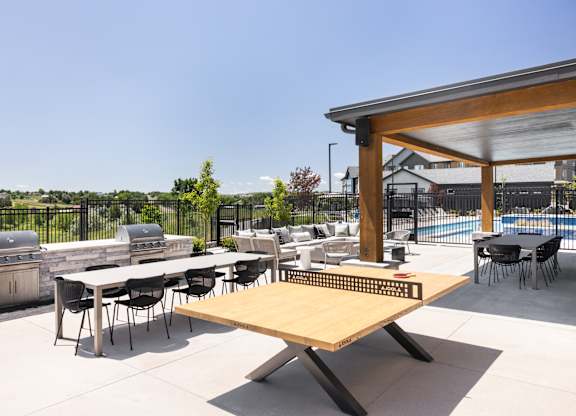 A table tennis table is in the middle of an outdoor patio.