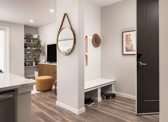 A modern kitchen with a white countertop and a round mirror on the wall.